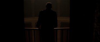 Movie still from “From Hell” (2001), directed by Allen Hughes – A man in a suit standing in front of a railing in the dark; Wide shot, Low angle