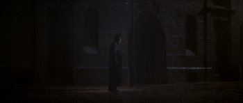 Movie still from “From Hell” (2001), directed by Allen Hughes – An old man in a black coat and hat walking in the dark; Wide shot, Over the shoulder angle