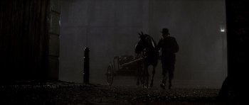 Movie still from “From Hell” (2001), directed by Allen Hughes – A man leading a horse and carriage down a dark street; Wide shot, Low angle
