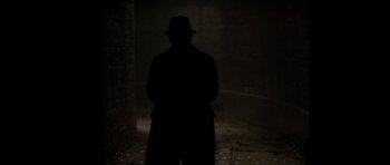 Movie still from “From Hell” (2001), directed by Allen Hughes – A man standing in the dark wearing a hat; Wide shot, Low angle