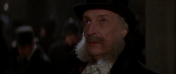 Movie still from “From Hell” (2001), directed by Allen Hughes – An old man with a beard wearing a top hat and a bow tie; Close Up shot, Over the shoulder angle