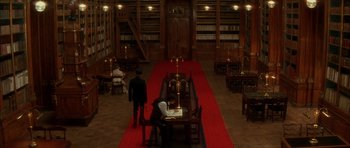 Movie still from “From Hell” (2001), directed by Allen Hughes – Two people are sitting at a table in a library; Extreme Wide shot, High angle