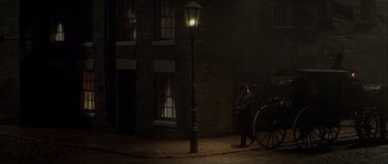 Movie still from “From Hell” (2001), directed by Allen Hughes – A man standing next to a lamp post at night; Extreme Wide shot, High angle