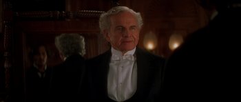 Movie still from “From Hell” (2001), directed by Allen Hughes – An older man wearing a tuxedo and bow tie; Close Up shot, Over the shoulder angle