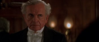 Movie still from “From Hell” (2001), directed by Allen Hughes – An older man wearing a tuxedo and a bow tie; Close Up shot, Over the shoulder angle