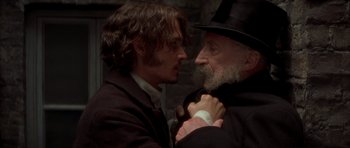 Movie still from “From Hell” (2001), directed by Allen Hughes – A man in a black hat and a man in a black suit; Close Up shot, Over the shoulder angle