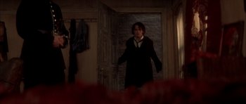 Movie still from “From Hell” (2001), directed by Allen Hughes – A man standing in front of an open door in a room; Medium shot, Over the shoulder angle