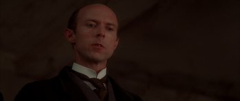 Movie still from “From Hell” (2001), directed by Allen Hughes – A man with a bald head wearing a suit and tie; Close Up shot, Low angle