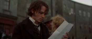 Movie still from “From Hell” (2001), directed by Allen Hughes – A man in a suit looking down at a paper; Close Up shot, High angle