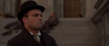 Movie still from “From Hell” (2001), directed by Allen Hughes – A man wearing a hat and a suit; Close Up shot, Low angle