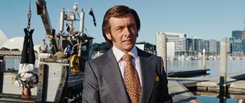 Movie still from “Frost/Nixon” (2008), directed by Ron Howard – A man in a suit and tie standing in front of a boat; Close Up shot, Low angle