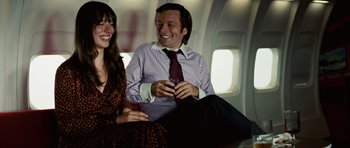 Movie still from “Frost/Nixon” (2008), directed by Ron Howard – A man and a woman sitting next to each other on a plane; Medium shot, Over the shoulder angle