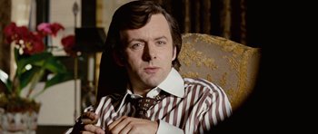 Movie still from “Frost/Nixon” (2008), directed by Ron Howard – A person sitting on a chair wearing a tie; Close Up shot, Over the shoulder angle