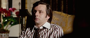 Movie still from “Frost/Nixon” (2008), directed by Ron Howard – A person sitting on a chair wearing a tie; Close Up shot, Over the shoulder angle
