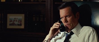 Movie still from “Frost/Nixon” (2008), directed by Ron Howard – A man talking on a phone while sitting in front of a bookshelf; Close Up shot, High angle