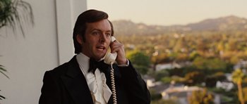 Movie still from “Frost/Nixon” (2008), directed by Ron Howard – A man in a tuxedo talking on a phone; Close Up shot, Over the shoulder angle