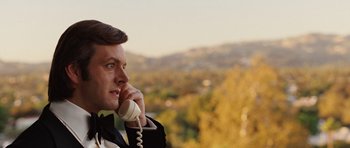 Movie still from “Frost/Nixon” (2008), directed by Ron Howard – A man talking on a phone while standing on a hill; Close Up shot, Over the shoulder angle