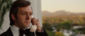 Movie still from “Frost/Nixon” (2008), directed by Ron Howard – A man holding a phone up to his ear while standing outside; Close Up shot, Low angle