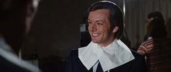 Movie still from “Frost/Nixon” (2008), directed by Ron Howard – A man in a suit and tie with a paper napkin around his neck; Close Up shot, Over the shoulder angle