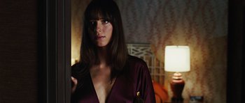 Movie still from “Frost/Nixon” (2008), directed by Ron Howard – A beautiful woman in a purple dress standing next to a lamp; Close Up shot, Over the shoulder angle