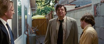 Movie still from “Frost/Nixon” (2008), directed by Ron Howard – A man wearing a suit and tie standing in a yard; Medium shot, Low angle