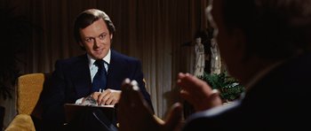 Movie still from “Frost/Nixon” (2008), directed by Ron Howard – A man sitting at a table in front of another man; Close Up shot, Over the shoulder angle