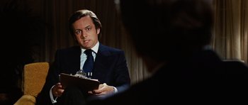Movie still from “Frost/Nixon” (2008), directed by Ron Howard – A man wearing a suit and tie holding a clipboard; Close Up shot, Over the shoulder angle