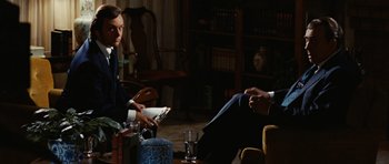 Movie still from “Frost/Nixon” (2008), directed by Ron Howard – Two men sitting in a living room talking to each other; Medium shot, Over the shoulder angle
