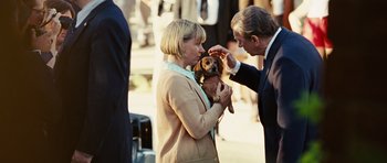 Movie still from “Frost/Nixon” (2008), directed by Ron Howard – A woman holding a small dog while a man holds it up; Medium shot, Over the shoulder angle