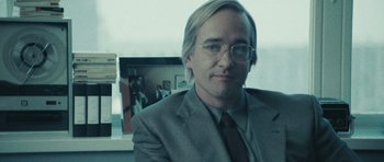 Movie still from “Frost/Nixon” (2008), directed by Ron Howard – A man in a suit and tie sitting in front of a picture; Close Up shot, Over the shoulder angle