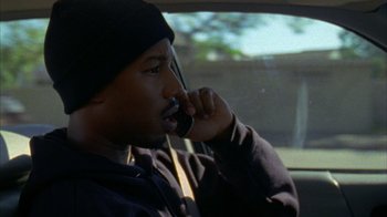 Movie still from “Fruitvale Station” (2013), directed by Ryan Coogler – A man talking on a cell phone while sitting in a car; Close Up shot, High angle