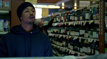 Movie still from “Fruitvale Station” (2013), directed by Ryan Coogler – A man standing in front of a wine display; Close Up shot, Over the shoulder angle
