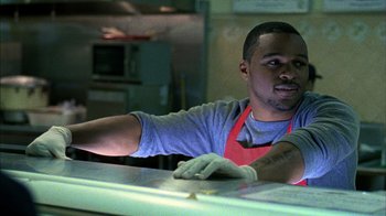 Movie still from “Fruitvale Station” (2013), directed by Ryan Coogler – A man wearing an apron leaning on a counter; Medium shot, Low angle