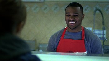 Movie still from “Fruitvale Station” (2013), directed by Ryan Coogler – A man wearing an apron smiles at the camera; Medium shot, Over the shoulder angle