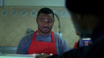 Movie still from “Fruitvale Station” (2013), directed by Ryan Coogler – A man wearing an apron is looking at another man in a kitchen; Close Up shot, Over the shoulder angle