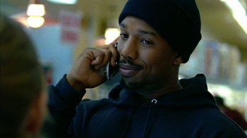 Movie still from “Fruitvale Station” (2013), directed by Ryan Coogler – A man talking on a cell phone while wearing a hat; Close Up shot, High angle
