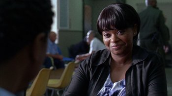 Movie still from “Fruitvale Station” (2013), directed by Ryan Coogler – A woman sitting at a table in front of a group of people; Close Up shot, Over the shoulder angle