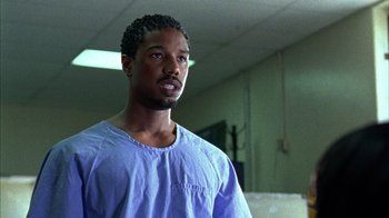 Movie still from “Fruitvale Station” (2013), directed by Ryan Coogler – A man in a hospital gown standing in a room; Close Up shot, Over the shoulder angle