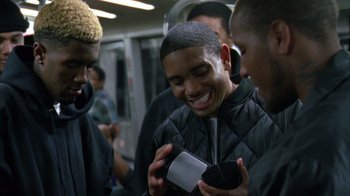 Movie still from “Fruitvale Station” (2013), directed by Ryan Coogler – A group of people on a train looking at their cell phones; Close Up shot, Over the shoulder angle