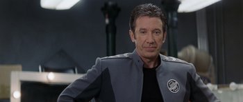 Movie still from “Galaxy Quest” (1999), directed by Dean Parisot – A man wearing a gray and black uniform; Close Up shot, Over the shoulder angle