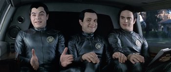 Movie still from “Galaxy Quest” (1999), directed by Dean Parisot – A group of three men in black suits sitting in the back of a car; Medium shot, High angle