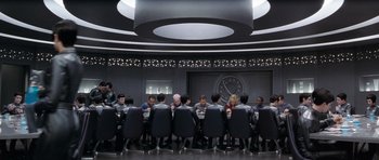 Movie still from “Galaxy Quest” (1999), directed by Dean Parisot – A group of people sitting at a table in front of a clock; Wide shot, Over the shoulder angle