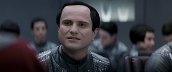 Movie still from “Galaxy Quest” (1999), directed by Dean Parisot – A man in a black and white outfit looking at the camera; Close Up shot, Over the shoulder angle