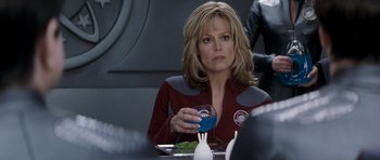 Movie still from “Galaxy Quest” (1999), directed by Dean Parisot – A woman sitting at a dinner table holding a drink; Close Up shot, Over the shoulder angle