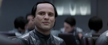 Movie still from “Galaxy Quest” (1999), directed by Dean Parisot – A man in a black and silver suit with a black wig; Close Up shot, Over the shoulder angle