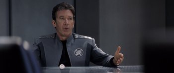 Movie still from “Galaxy Quest” (1999), directed by Dean Parisot – A man wearing a gray and black uniform; Close Up shot, Over the shoulder angle