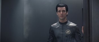 Movie still from “Galaxy Quest” (1999), directed by Dean Parisot – A man in a black and silver suit standing in front of a wall; Close Up shot, Over the shoulder angle
