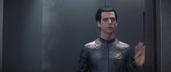 Movie still from “Galaxy Quest” (1999), directed by Dean Parisot – A man in a black and silver suit standing in front of a gray wall; Close Up shot, Over the shoulder angle