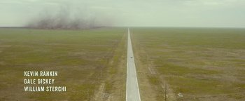 Movie still from “Hell or High Water” (2016), directed by David Mackenzie – An aerial view of an empty road in the middle of a field; Extreme Wide shot, High angle