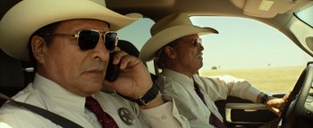 Movie still from “Hell or High Water” (2016), directed by David Mackenzie – Two men sitting in the back of a car talking on a cell phone; Medium shot, Low angle